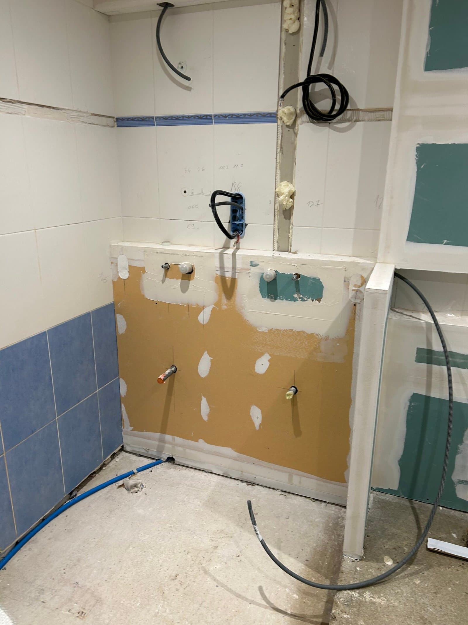 Chantier de rénovation de salle de bain en cours : alimentations d'eau en attente et préparation de l'étanchéité
